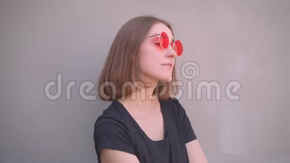 年轻酷酷的白种人女孩戴着红色太阳镜肩上戴着皮夹克微笑着看着视频的预览图