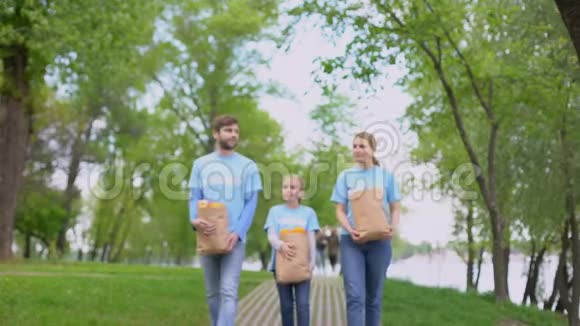 志愿者家庭步行公园拿着装有苹果和橘子的纸袋帮忙视频的预览图
