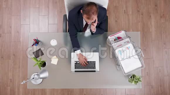 穿西装的商人在电话上聊天在笔记本电脑上打字视频的预览图
