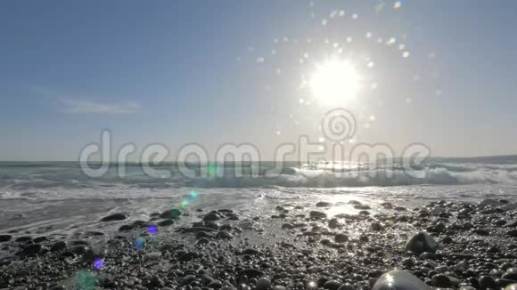 令人惊叹的海景海浪冲刷鹅卵石海滩在明亮的阳光下观看视频的预览图