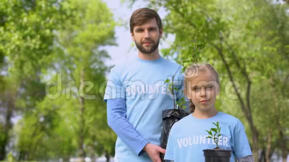 微笑的父亲和女儿持有绿色植物树苗重新造林基金视频的预览图