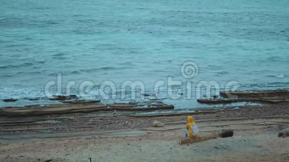 美丽的女人独自走在海边的石滩上海浪在岸边拍打埃及的西奈山在视频的预览图
