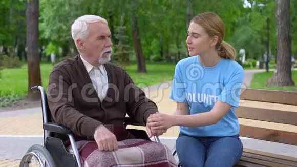相当漂亮的女性志愿者支持轮椅上的老年男性患者视频的预览图