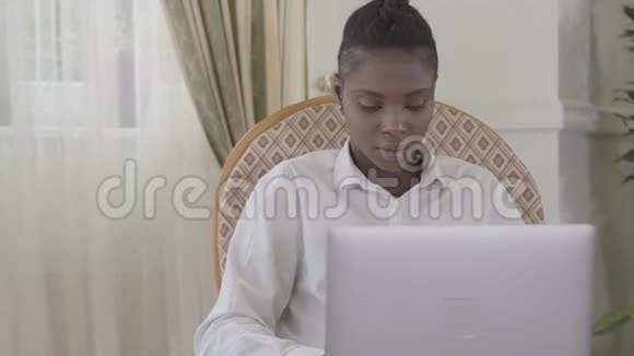 一位美国女性在舒适的生活中坐在扶手椅上专注地工作着一天的笔记本电脑视频的预览图