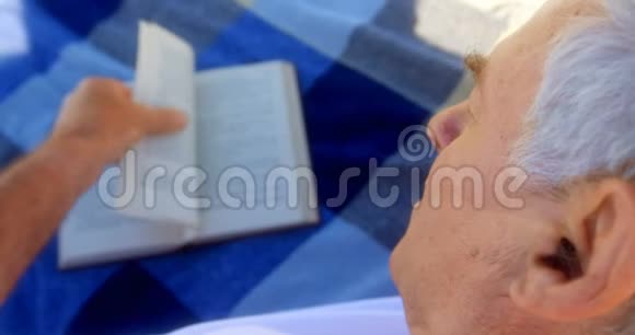 活跃的高加索老人在沙滩上看书的特写4k视频的预览图