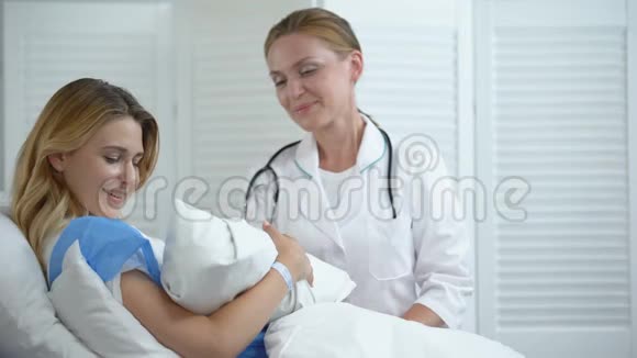 医生和母亲抱着新生儿对着镜头微笑皮肤与皮肤接触视频的预览图