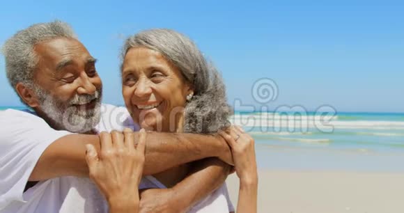 正面观看快乐活跃的非裔美国人高级男子拥抱海滩上的高级妇女4k视频的预览图
