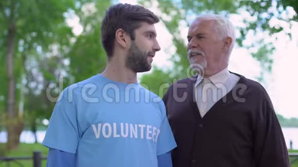 年轻的男性志愿者和成熟的绅士互相微笑社会支持视频的预览图