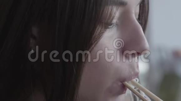 用筷子夹起吃面的年轻女子的脸中餐厅晚餐美味可口的开胃菜视频的预览图