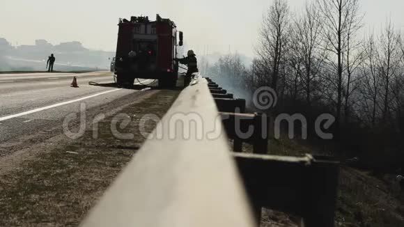消防队员从对面的消防车上解开消防水带扑灭森林中的火灾和干草视频的预览图