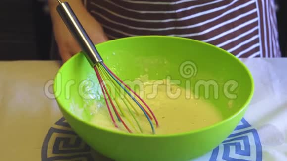 在家庭厨房的绿色碗里女性手的特写慢动作给面粉加水烹饪煎饼视频的预览图