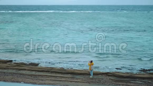 美丽的女人在海边的石滩上散步和拍照海浪在海岸上破浪前进埃及西奈视频的预览图