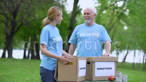 志趣相投的志愿者们手捧着捐款箱在公园里微笑无私奉献视频的预览图