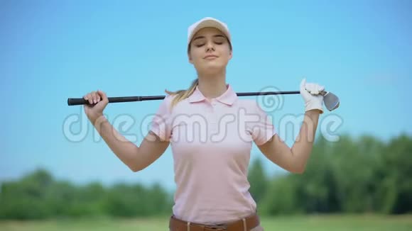 在高尔夫球比赛前在手中拿着球杆进行漂亮的运动女士训练运动视频的预览图
