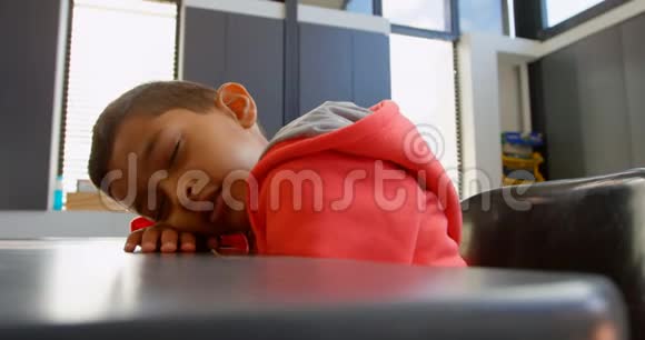 4k教室里睡在课桌上的亚洲小学生的侧视图视频的预览图