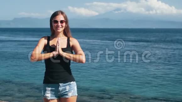 年轻漂亮女孩做瑜伽运动的肖像背景海洋慢动作视频的预览图