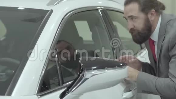 穿西装的可爱自信大胡子商人在汽车经销商处检查新购买的汽车视频的预览图