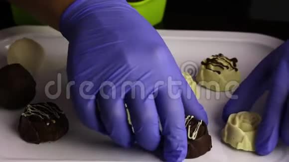 一个戴着橡胶手套的人把糖果放在白色和黑色巧克力中托盘上的绳子国际糖果日视频的预览图