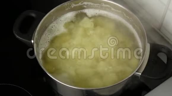 闭合一个女人的手在一壶开水里搅拌土豆视频的预览图