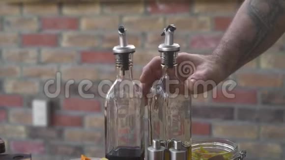 厨师在厨房做饭时从玻璃瓶里倒橄榄油准备时倒橄榄油的人视频的预览图