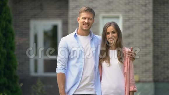 微笑的夫妇竖起大拇指站在房子旁边买房地产视频的预览图
