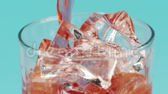 将红色饮料倒入装有冰块的玻璃杯中置于青色背景下特写慢镜头拍摄红色视频的预览图