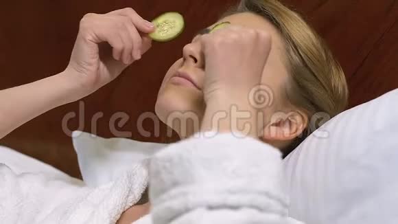 年轻漂亮的女人用黄瓜片天然护肤品有机产品视频的预览图