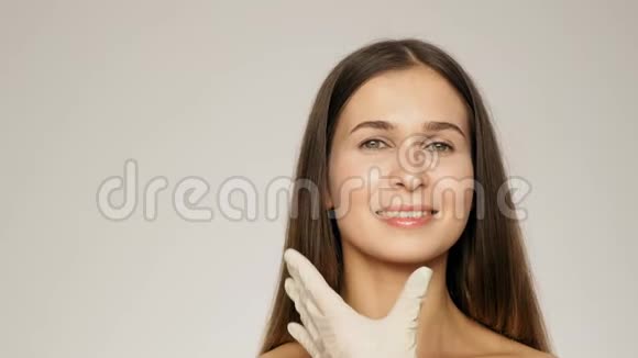 双手戴手套在前额区域注射前拿着注射器给美丽的微笑的女人慢动作视频的预览图