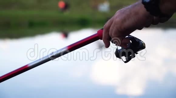 关闭手柄旋转与鱼竿卷筒与湖背景一个人在一个大湖上钓鱼视频的预览图