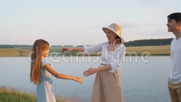 女孩拥抱她的母亲湖上的家庭户外娱乐活动视频的预览图