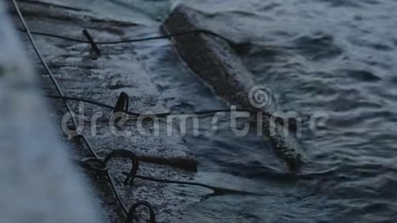 傍晚时分冰冷的暗海波缓慢地拍打着古老的水泥防波堤视频的预览图