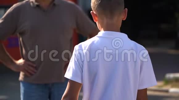 一对父子格雷马球爸爸用白色马球拍拍儿子的肩膀赞许视频的预览图