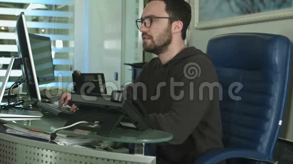 一名男性办公室工作人员在一间明亮的办公室工作时的侧视视频的预览图