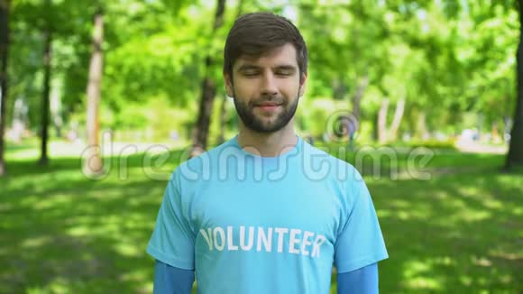 英俊的男性志愿者站在公园微笑摄像机生态修复视频的预览图