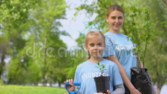 小女孩和年轻妇女抱着树苗生态志愿项目视频的预览图