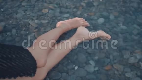 一个年轻的女孩躺在海边没有知觉没有动作海水中女孩腿的特写视频的预览图
