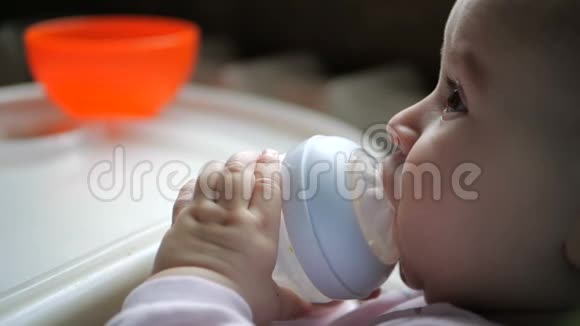 可爱的婴儿坐着用滴管缓慢地从瓶子里喝水视频的预览图