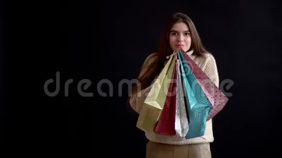 可爱的女孩白种人的外表紧紧地抱着一大堆五颜六色的礼品袋视频的预览图