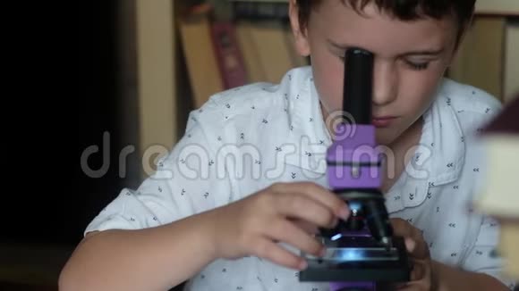 那个男孩透过显微镜看由于疲劳他的双手揉过眼睛视频的预览图