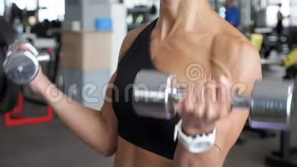 不知名的运动女性在健身房为双手握着哑铃的肱二头肌做了一套代表运动视频的预览图