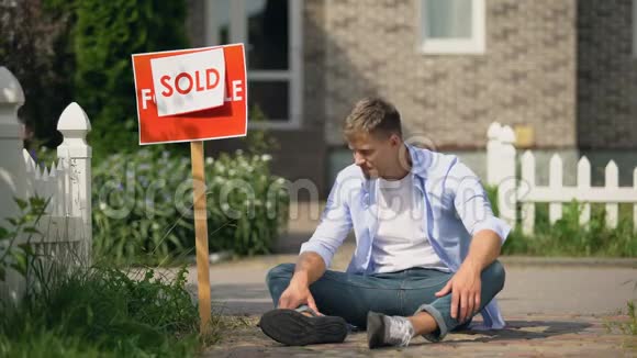 男人哭着坐在卖招牌附近的地上国家以财产为债视频的预览图
