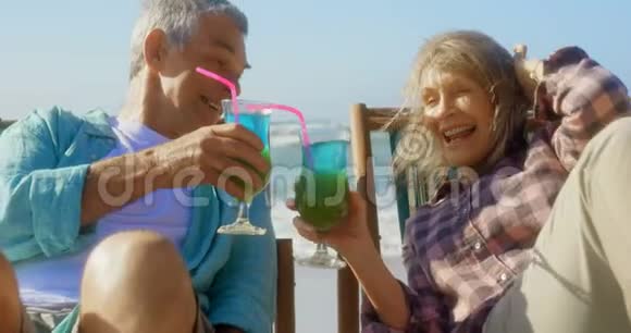 活跃的高加索夫妇在海滩上品尝一杯鸡尾酒的正面景色视频的预览图