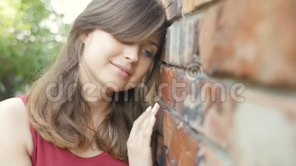 年轻可爱的美丽女孩靠近红砖墙微笑和调情梦幻浪漫的女人走在户外女性的情感波视频的预览图
