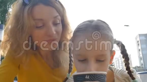 夏天穿着黄色衬衫的美丽年轻母亲和她的小女儿一起放松的特写照片视频的预览图