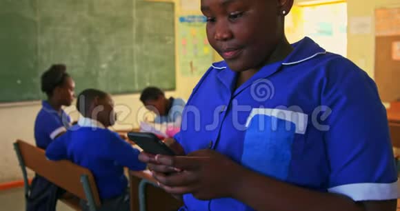在一所乡村学校的教室里使用智能手机的女学生视频的预览图