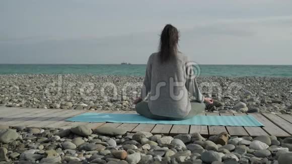 孤独的女运动员正享受海景双腿交叉坐在沙滩上视频的预览图
