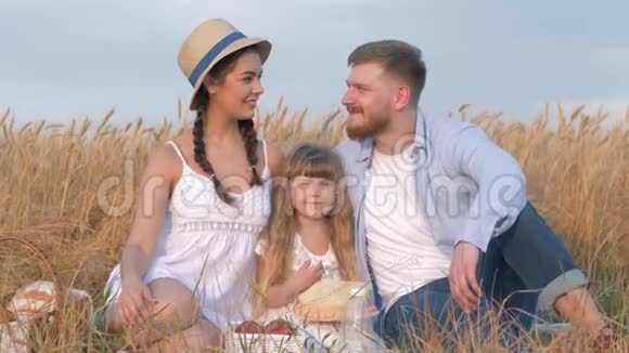 幸福的家庭画像这对年轻的夫妇坐在一起靠近他们的女儿在露天郊游收获视频的预览图
