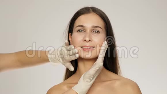 美容师双手手套触摸女性客户的面部和颈部然后进行慢动作视频的预览图