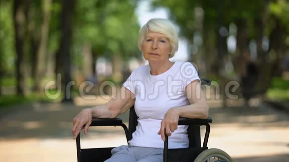 坐在轮椅上看着医院公园摄像机的沮丧的老年妇女视频的预览图
