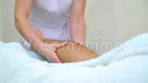 在水疗沙龙中女性按摩师按摩青年男子毛胫的倾斜度视频的预览图